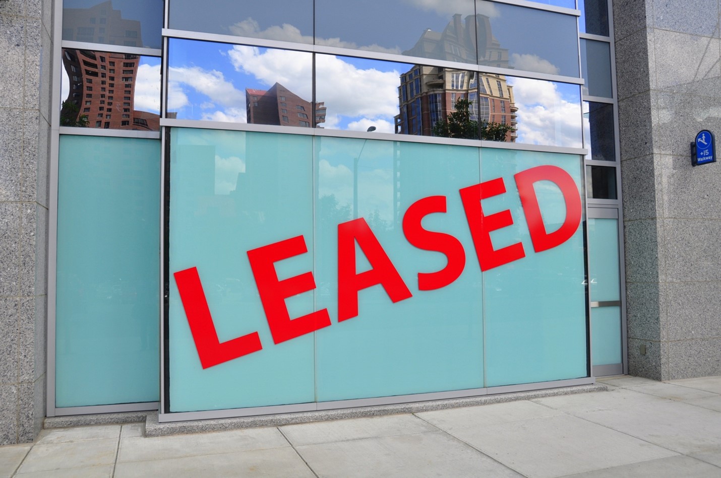 Large building with leased sign in front of it